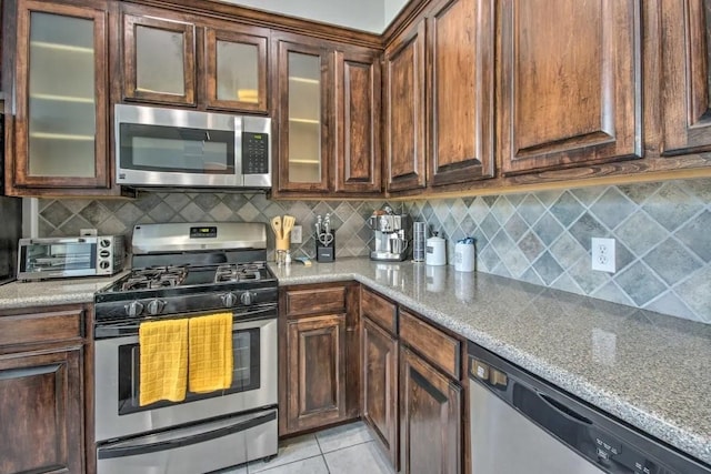 207 Knox St, Houston, TX 77007 - kitchen with light tile patterned floors, light stone countertops, a toaster, stainless steel appliances, and backsplash