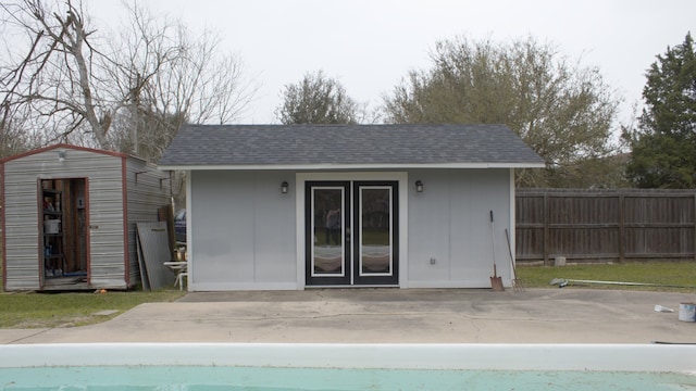rear view of house featuring a patio, roof with shingles, an outdoor structure, and fence