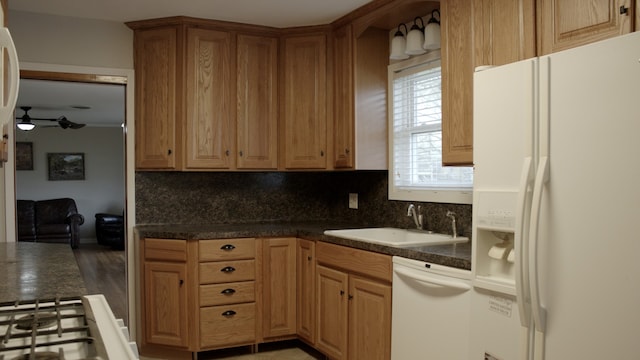 kitchen with white appliances, ceiling fan, decorative backsplash, a sink, and dark countertops
