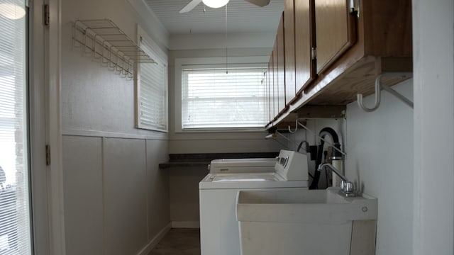 clothes washing area featuring washing machine and clothes dryer, ceiling fan, a decorative wall, cabinet space, and a sink