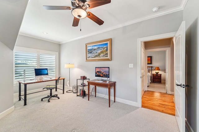 carpeted home office featuring baseboards, ornamental molding, and a ceiling fan