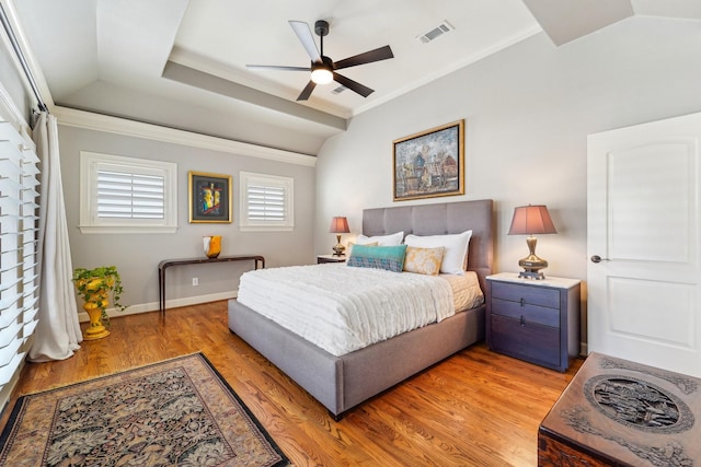 bedroom featuring baseboards, light wood-type flooring, ornamental molding, visible vents, and lofted ceiling