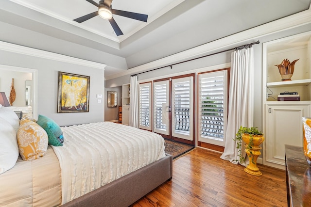 bedroom featuring crown molding, ceiling fan, a tray ceiling, access to exterior, and wood finished floors