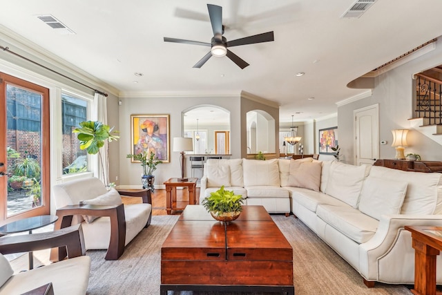 living area featuring ornamental molding, visible vents, and ceiling fan with notable chandelier