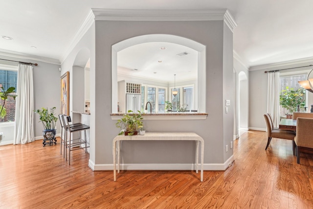 entryway featuring arched walkways, light wood finished floors, visible vents, and baseboards