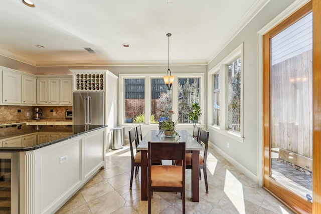 dining room with light tile patterned floors, ornamental molding, visible vents, wine cooler, and baseboards
