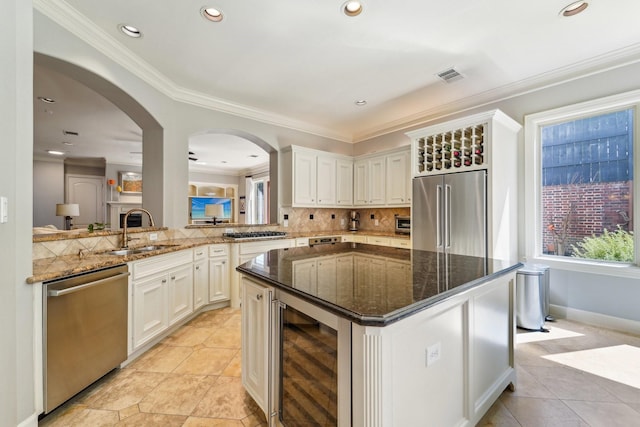 kitchen featuring visible vents, a sink, beverage cooler, stainless steel appliances, and decorative backsplash
