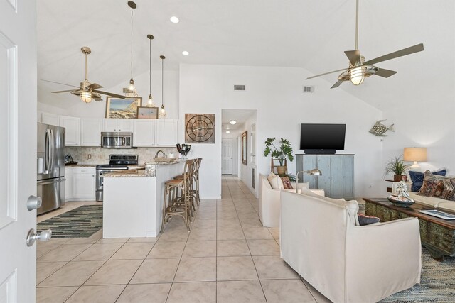 22102 Pecos Dr, Galveston, TX 77554 - living area featuring light tile patterned flooring, visible vents, high vaulted ceiling, and a ceiling fan