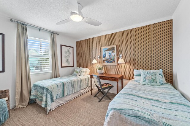 22102 Pecos Dr, Galveston, TX 77554 - carpeted bedroom with wallpapered walls, a ceiling fan, an accent wall, and a textured ceiling