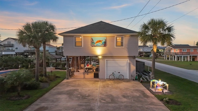 22102 Pecos Dr, Galveston, TX 77554 - view of front facade with concrete driveway, a garage, and a front yard