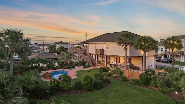 22102 Pecos Dr, Galveston, TX 77554 - rear view of house with fence, stairs, a yard, an attached garage, and a patio