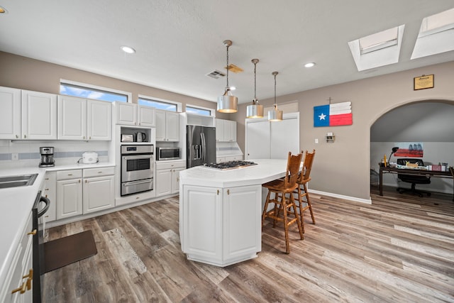 12604 Pegasus Dr, Willis, TX 77318 - kitchen with a kitchen island, a breakfast bar area, a skylight, stainless steel appliances, and a warming drawer