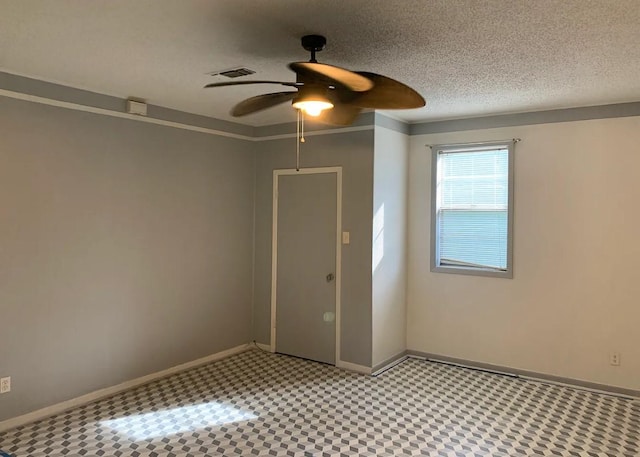empty room featuring visible vents, a ceiling fan, baseboards, and a textured ceiling