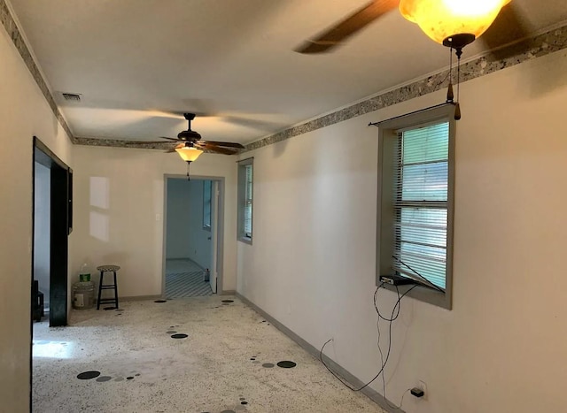unfurnished room featuring speckled floor, a ceiling fan, visible vents, and baseboards