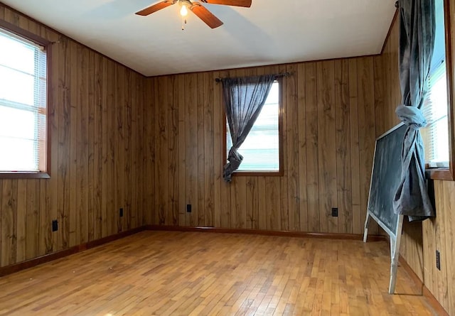 empty room with light wood-style flooring, a ceiling fan, and baseboards