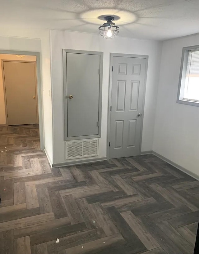 corridor with visible vents, baseboards, and a textured ceiling
