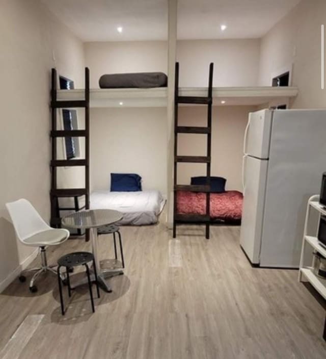 bedroom featuring wood finished floors, baseboards, and freestanding refrigerator