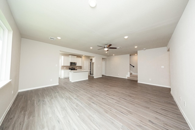 3626 Spy Glass Hill Dr, Montgomery, TX 77356 - unfurnished living room featuring stairs, visible vents, a ceiling fan, baseboards, and light wood-style floors