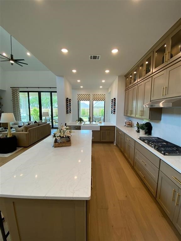 12039 Lake View Blvd, Mont Belvieu, TX 77523 - kitchen featuring stainless steel gas stovetop, light wood-style floors, recessed lighting, light stone counters, and a center island