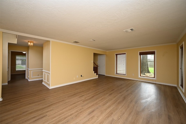 unfurnished room with visible vents, crown molding, and wood finished floors