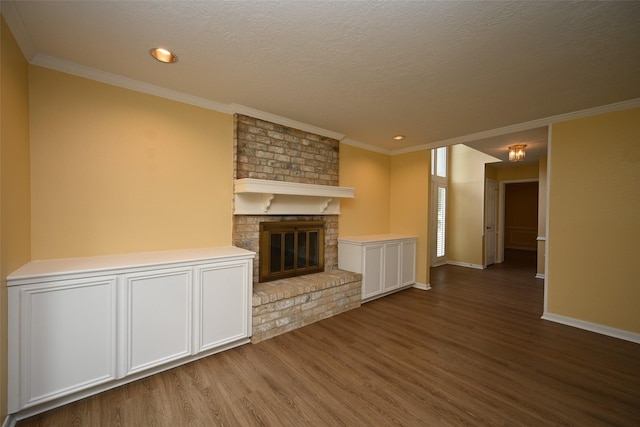unfurnished living room with a textured ceiling, ornamental molding, wood finished floors, a brick fireplace, and baseboards