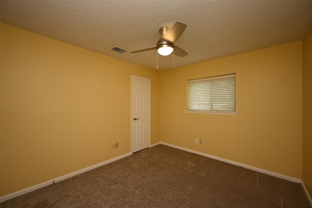 spare room featuring visible vents, baseboards, a ceiling fan, and dark colored carpet