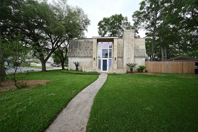 exterior space with a chimney, fence, a front lawn, and brick siding