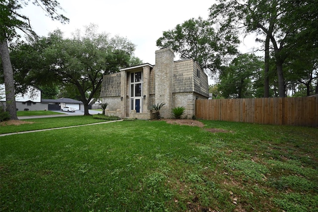 view of home's exterior with a yard, brick siding, fence, and a chimney