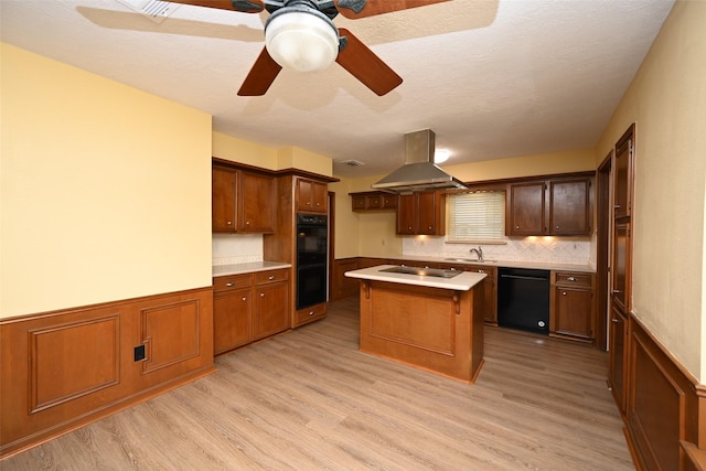 kitchen with a sink, light countertops, light wood-type flooring, black appliances, and island exhaust hood