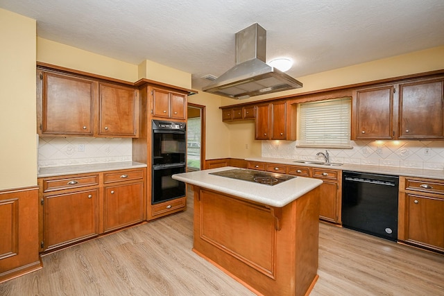kitchen with island range hood, light wood finished floors, a sink, and black appliances