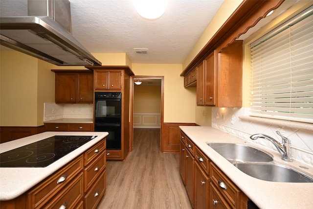 kitchen with exhaust hood, visible vents, black appliances, a wainscoted wall, and a sink