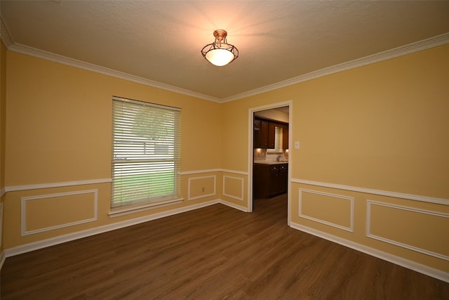 spare room with a decorative wall, wainscoting, crown molding, and dark wood finished floors