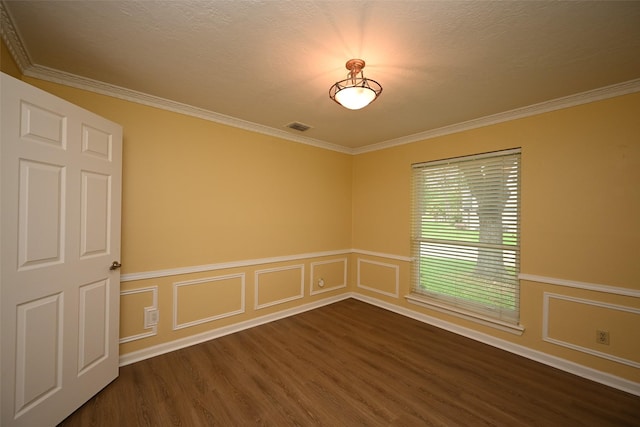 empty room with a textured ceiling, ornamental molding, visible vents, a wainscoted wall, and dark wood-style floors