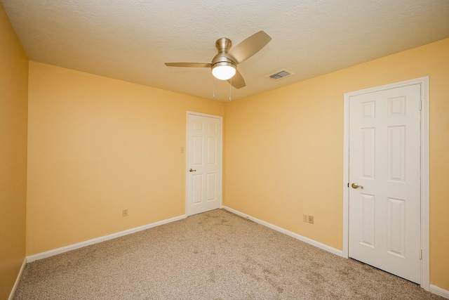 spare room with light carpet, ceiling fan, baseboards, and visible vents