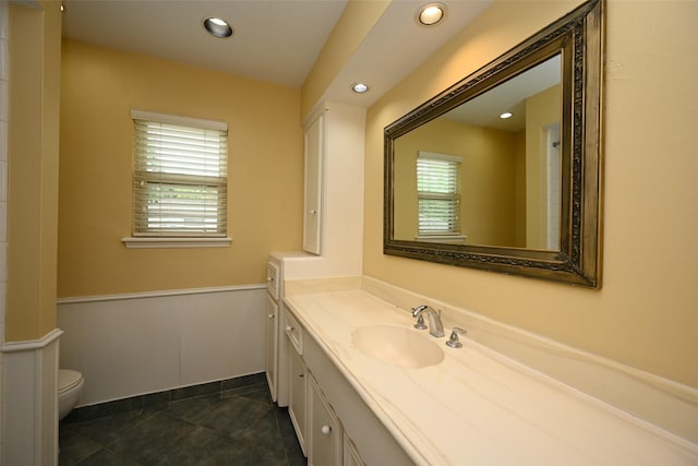 bathroom with toilet, recessed lighting, vanity, wainscoting, and tile patterned floors