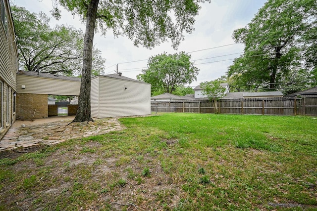 view of yard with a fenced backyard, an outdoor structure, and a storage unit