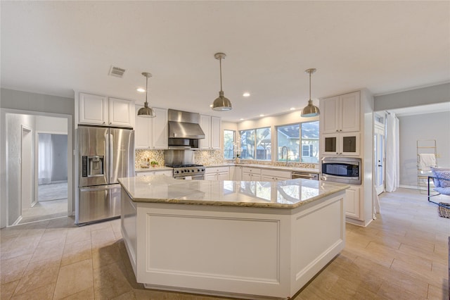 kitchen featuring backsplash, a kitchen island, appliances with stainless steel finishes, white cabinets, and wall chimney exhaust hood