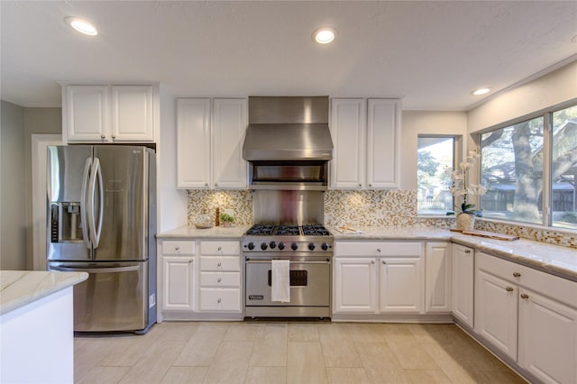 kitchen featuring white cabinetry, recessed lighting, appliances with stainless steel finishes, wall chimney range hood, and decorative backsplash