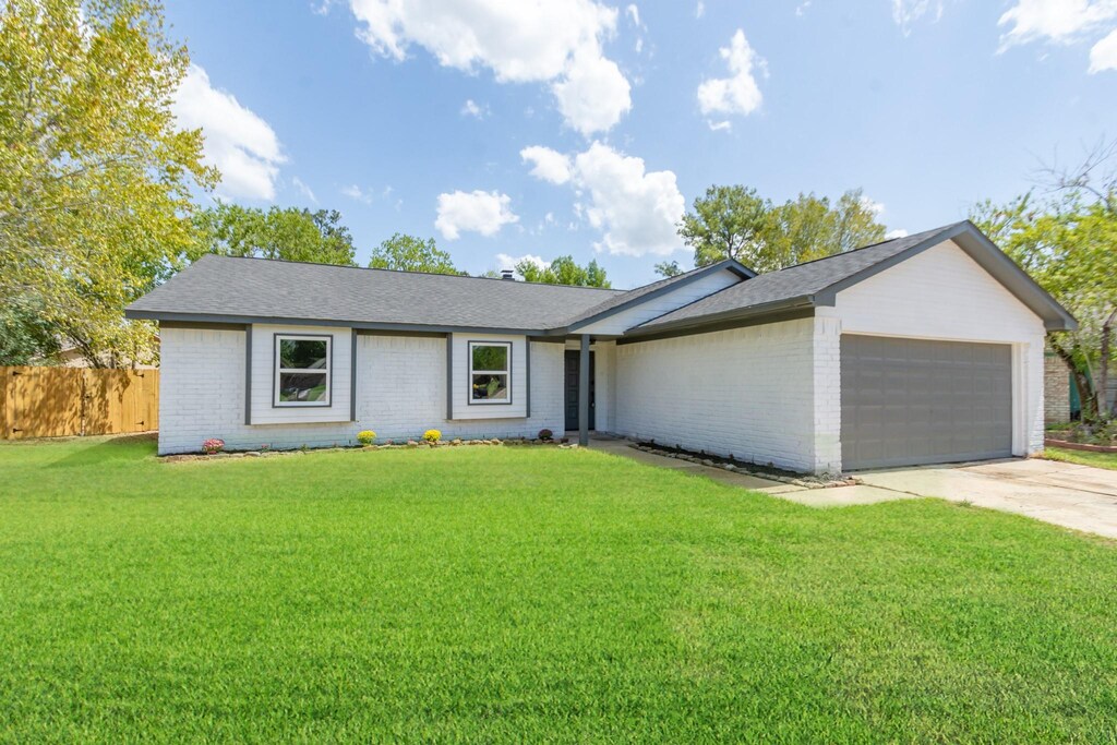 9813 Wren Ct, Conroe, TX 77385 - view of front of house with a front lawn, a garage, fence, and brick siding