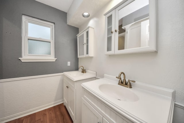 12635 Ivyforest Dr, Cypress, TX 77429 - bathroom with two vanities, wood finished floors, a sink, and baseboards