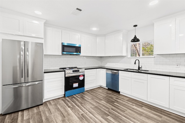 301 Pineland Dr, Trinity, TX 75862 - kitchen featuring visible vents, a sink, dark countertops, wood finished floors, and stainless steel appliances