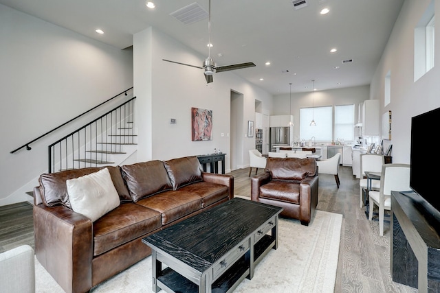 living room featuring a ceiling fan, stairway, visible vents, light wood-style floors, and recessed lighting