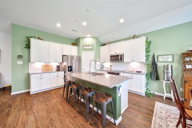 139 Jim Hall Ln, New Waverly, TX 77358 - kitchen with a sink, appliances with stainless steel finishes, decorative backsplash, a breakfast bar area, and recessed lighting