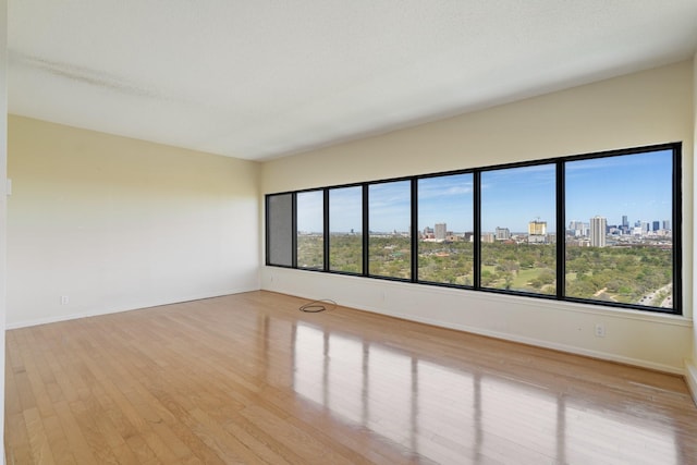 spare room featuring wood finished floors, baseboards, and a city view