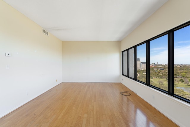 spare room featuring baseboards, a view of city, visible vents, and light wood-style floors