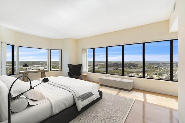 bedroom featuring a city view, visible vents, multiple windows, and wood finished floors