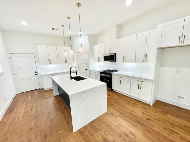 3038 Webster St, Houston, TX 77004 - kitchen featuring a sink, white cabinets, gas range, stainless steel microwave, and backsplash