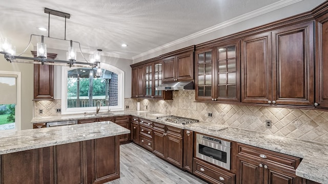 kitchen featuring under cabinet range hood, a sink, light wood-style floors, light stone countertops, and appliances with stainless steel finishes