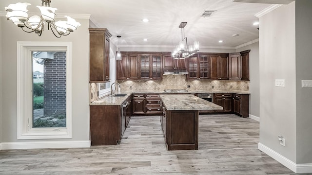 kitchen with stainless steel appliances, a kitchen island, under cabinet range hood, a sink, and a notable chandelier