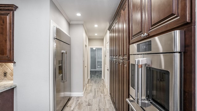 kitchen featuring decorative backsplash, baseboards, ornamental molding, appliances with stainless steel finishes, and light wood-style floors